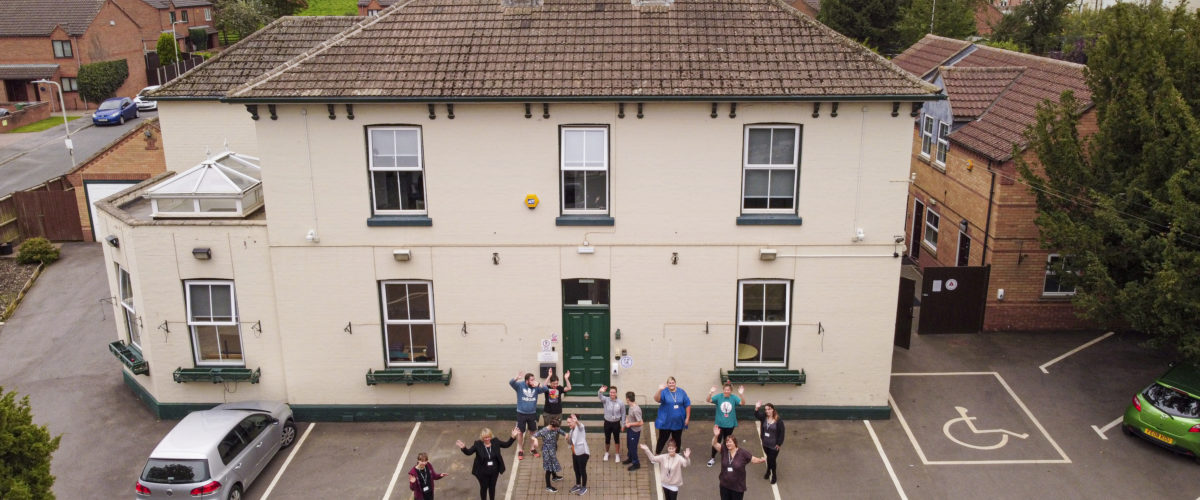 Aerial shot of Homefield College main site, with staff and students standing in front waving