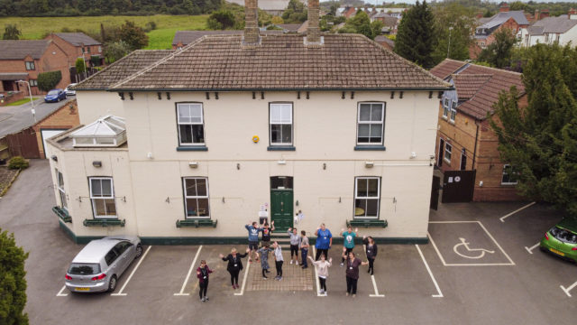 Aerial shot of Homefield College main site, with staff and students standing in front waving