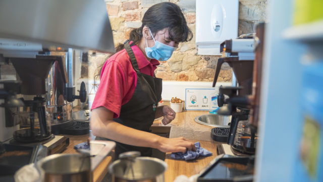 Student wiping work surface in Barrow of Treats