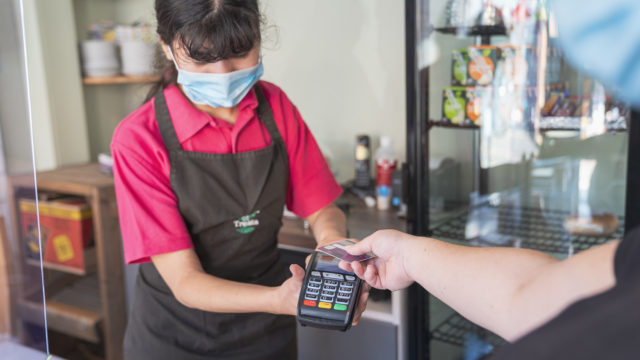 Student offering card machine to paying customer