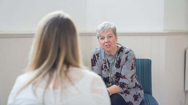 Staff member having a formal conversation with another person, both sat down