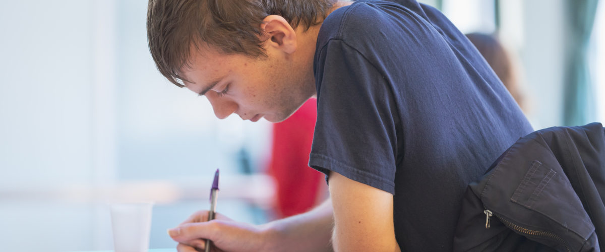 Student at desk holding pen concentrating on worksheet