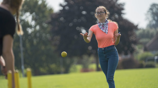 Student throwing cricket ball in park