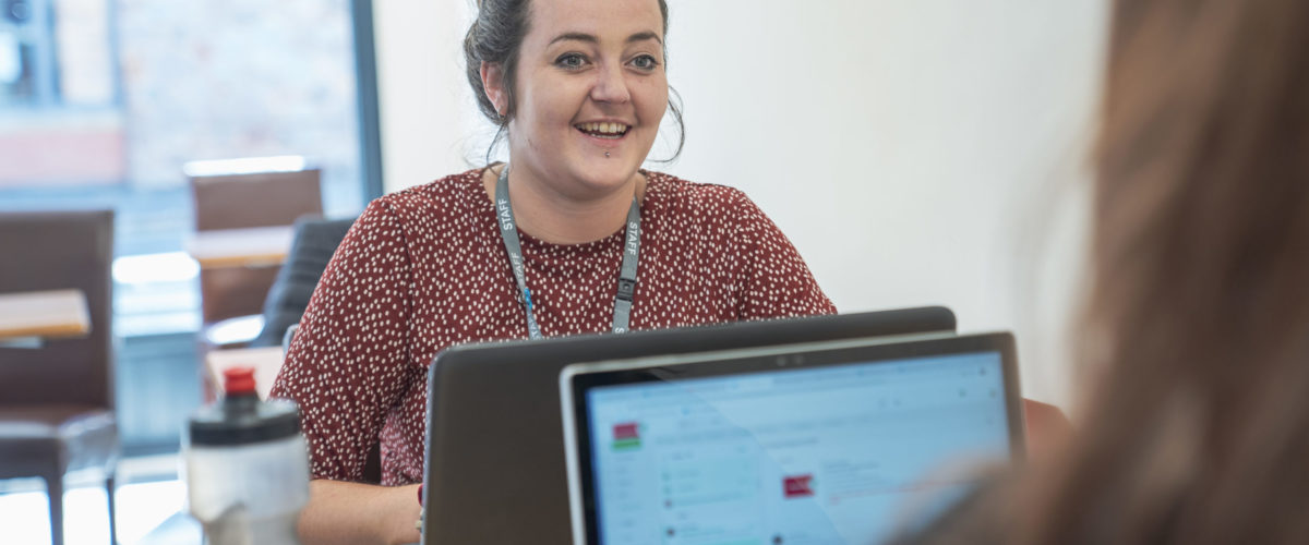 Staff member smiling in conversation with another person