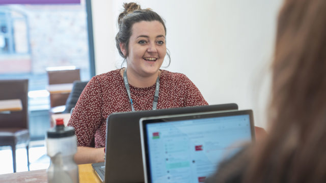 Staff member smiling in conversation with another person