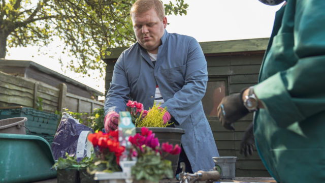 Student creating a flower display in a plant pot