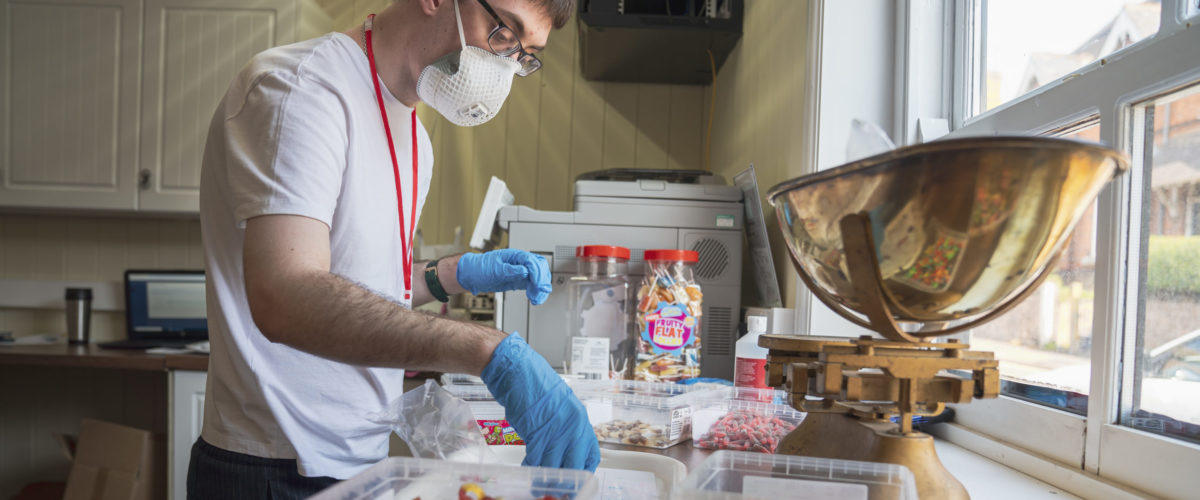 Student working in the sweet shop weighing sweets