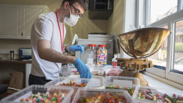 Student working in the sweet shop weighing sweets