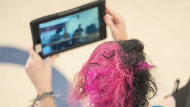 Aerial shot of a person holding an ipad taking a photo of students