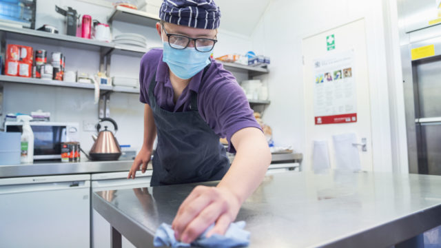 Student wiping down industrial kitchen