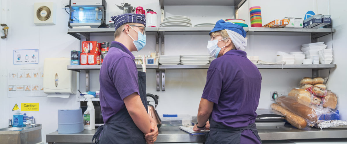 Student and staff conversing in commercial kitchen