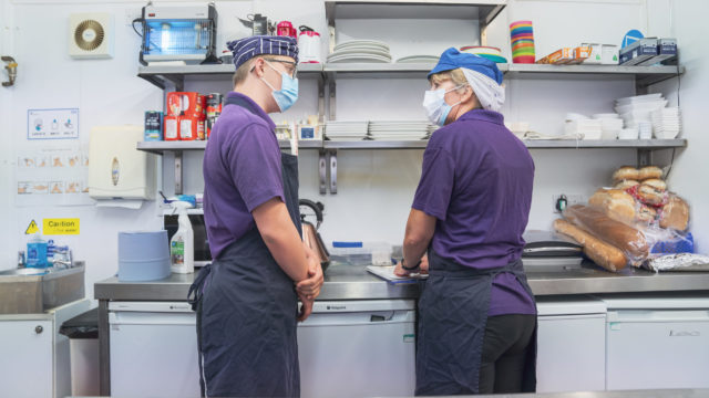 Student and staff conversing in commercial kitchen