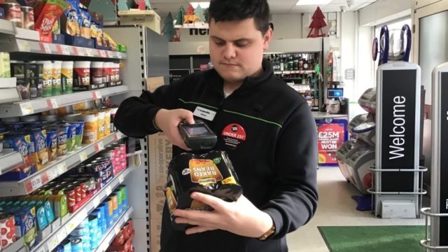 Student working in the co-op scanning barcode of baked beans