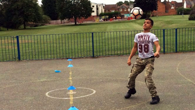 Student playing keepy-uppy with a football