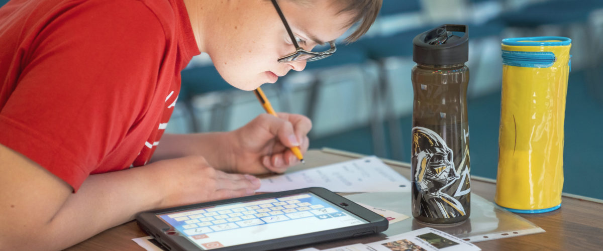 Student using ipad to help answer worksheet