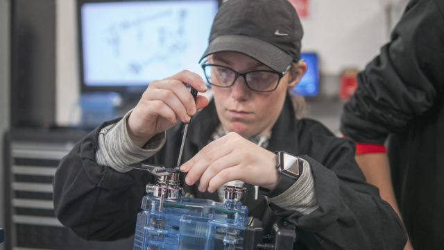 Student using tools on motor vehicle component