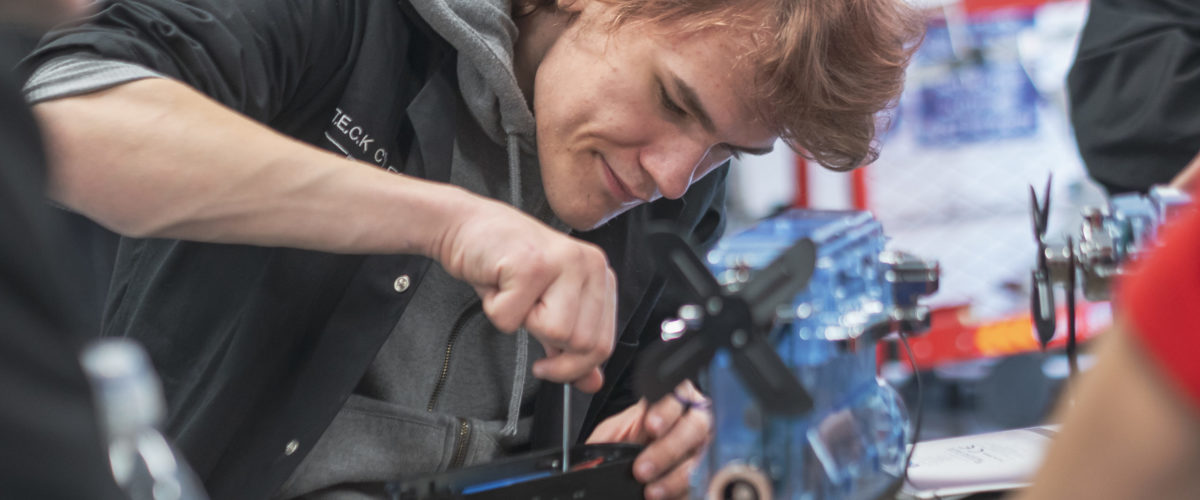 Student using tools on practice engine parts