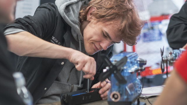 Student using tools on practice engine parts