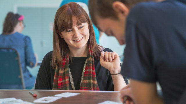 Staff member smiling whilst helping a student in session