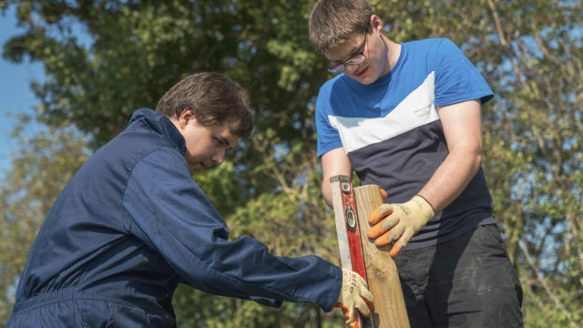 Students using level measure on fencepole