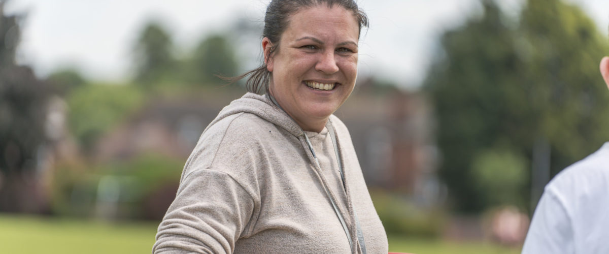 Staff member smiling whilst spinning a hoola-hoop