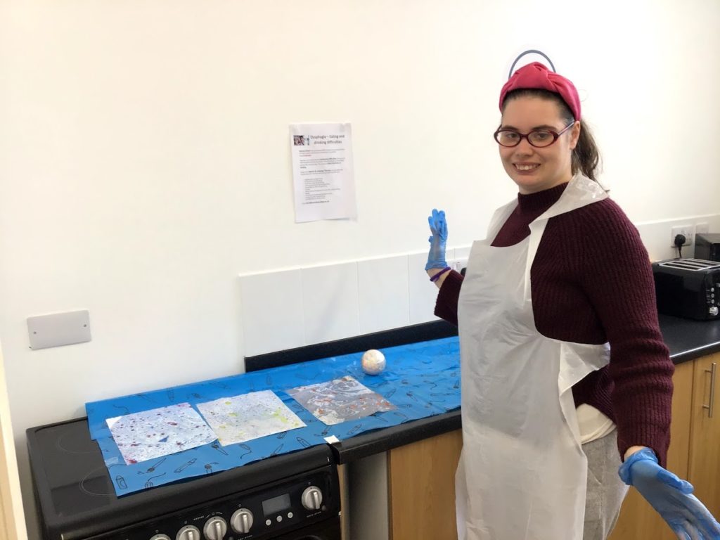 Student posing with her three marbled pieces of artwork