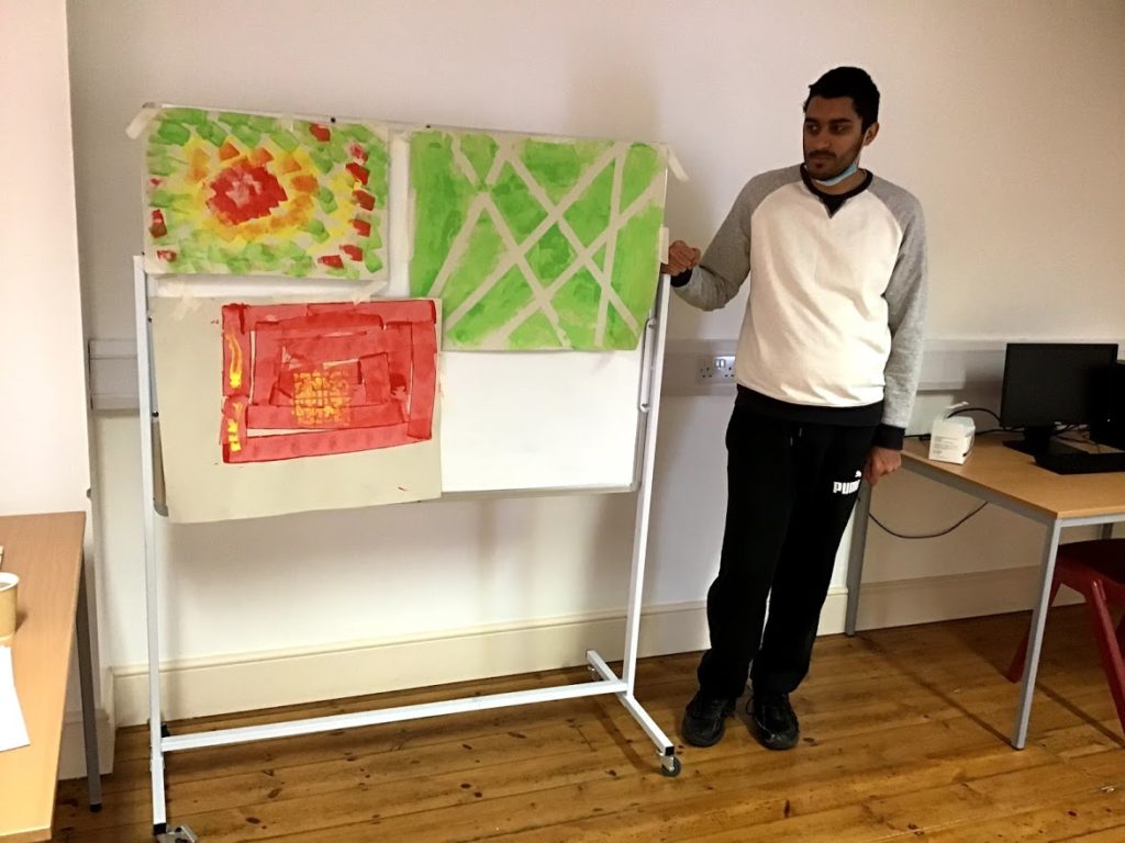 Student stood next to three paintings of different line patterns