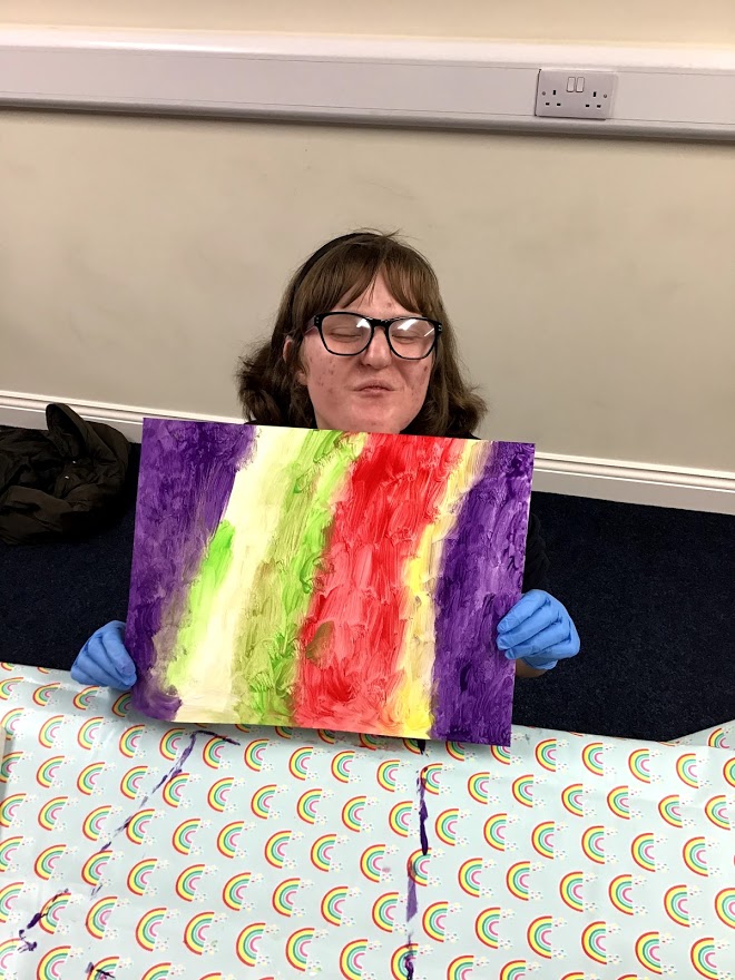 Student smiling holding canvas of paint lines