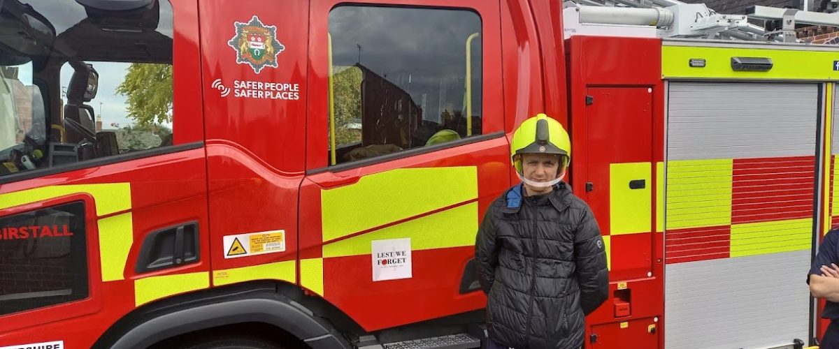 Student wearing helmet in front of fire engine