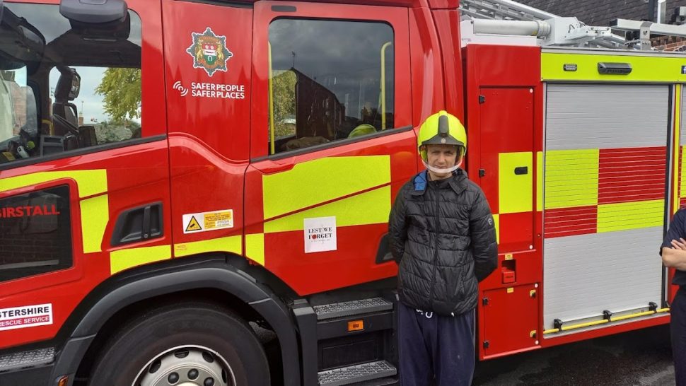 Student wearing helmet in front of fire engine