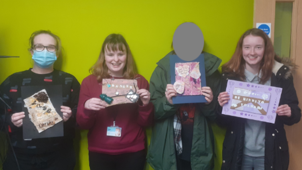 Four students holding up their mixed media creations