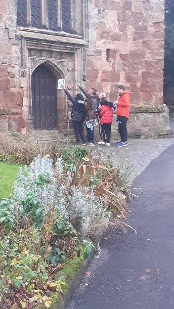 Students in front of a church pointing upwards to a clue answer