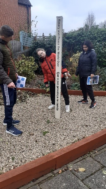 Students reading a sign post that says Rotary and Peace the World Over