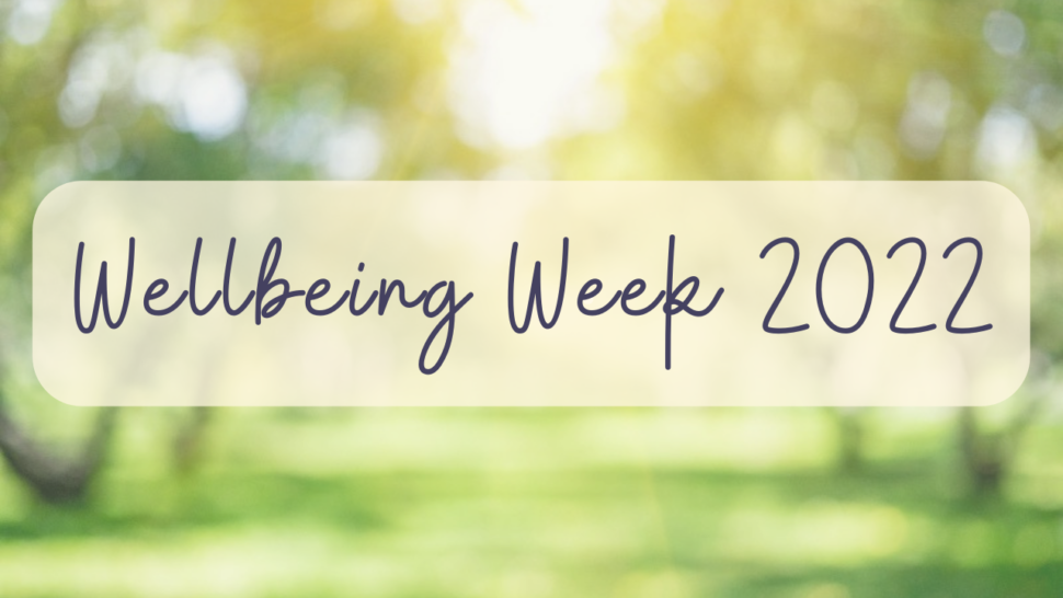 Text reads "wellbeing week 2022" on a blurred background of greenery