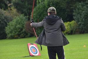 Student firing archery arrow at distant target