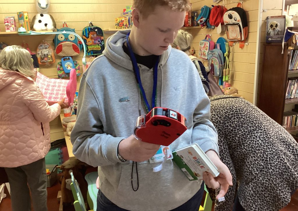 Student Jack labelling products with price labels in the charity shop during his work placement at Shuttlewood Clarke Foundation.