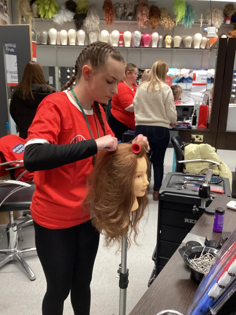 Skye working on her final hairdressing look, brushing the mannequin's hair