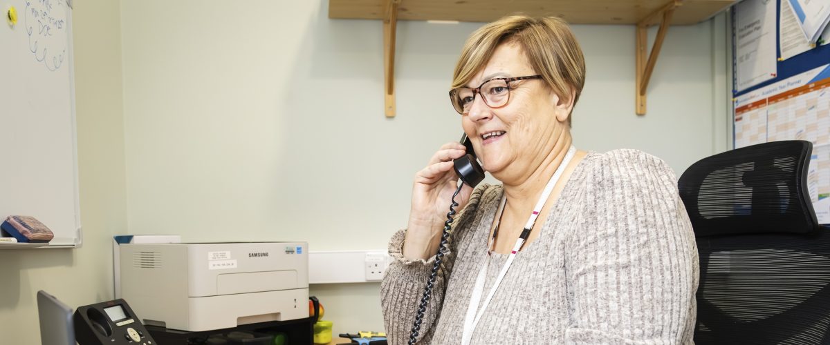Staff member smiling whilst answering the phone