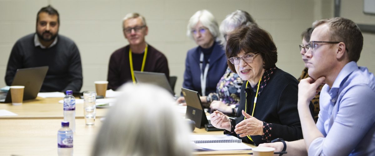 A group of trustees engage in conversation during a meeting.