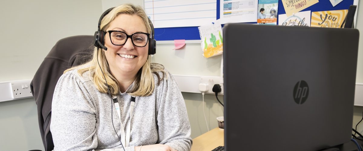 Staff member smiling at the camera from behind their desk