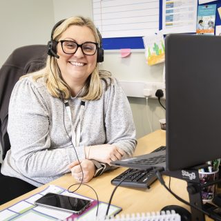 Staff member smiling at the camera from behind their desk