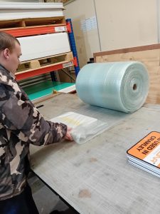 Student Elliott packaging a product within the Nuneaton Signs warehouse