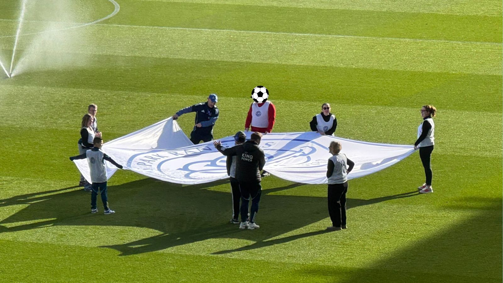 A picture of our students and staff holding the flag over the football field.