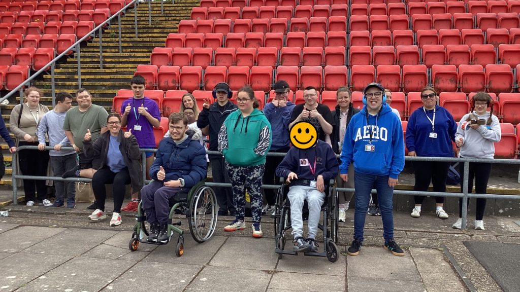 the entire group of attending staff and students smiling at the camera in front of the stadium seats