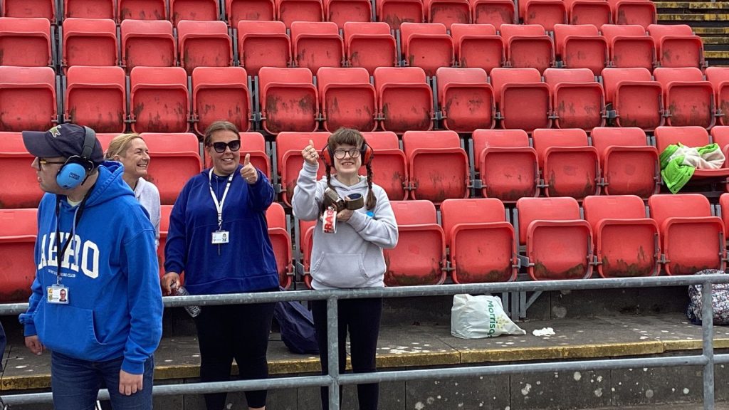 two students and two staff members doing a thumbs-up and smiling at the camera