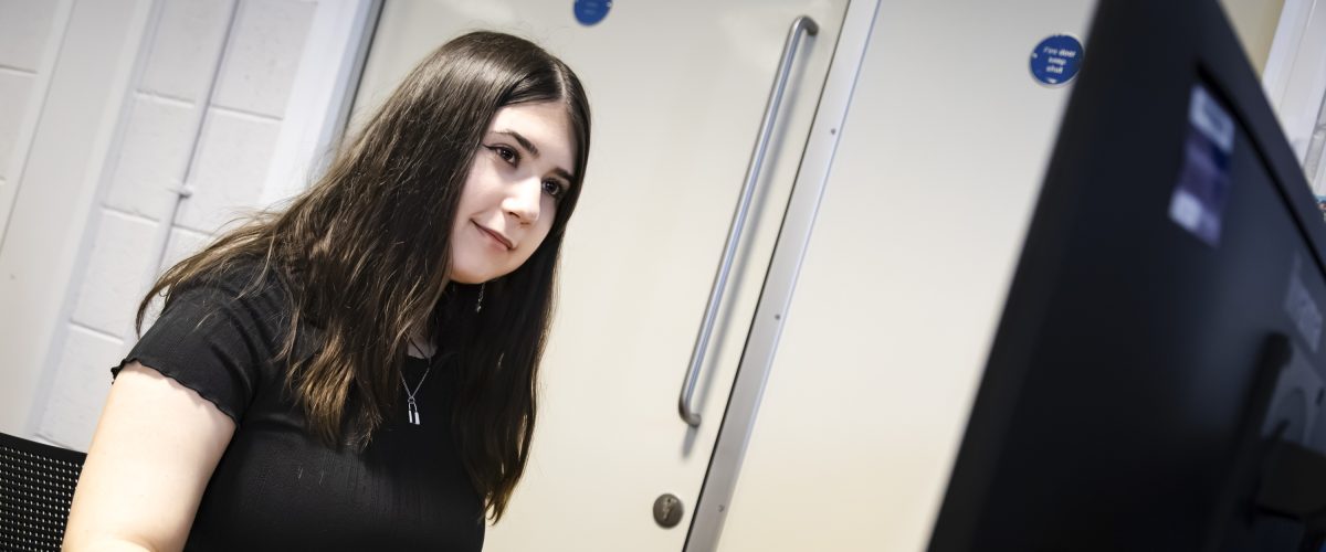 Staff member smiling whilst working at the computer