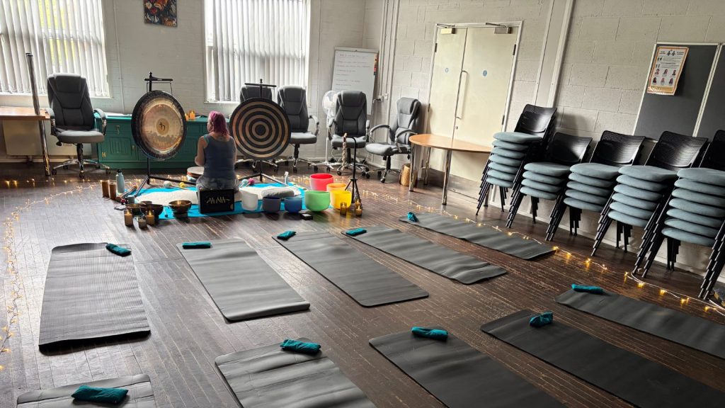 THe yoga instructor setting up the yoga room with gongs, floor mats, weights, fairy lights and fake candles.