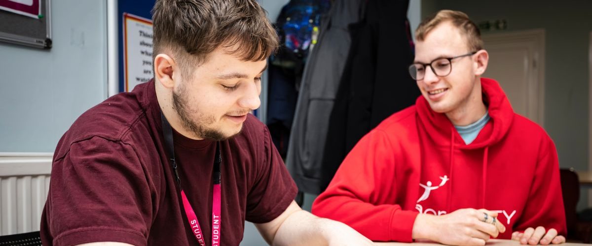 a photo of two students at a table discussing a topic together