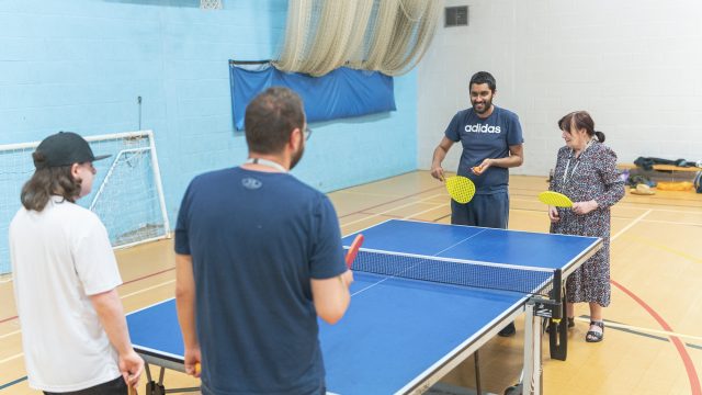 Students playing table tennis with staff