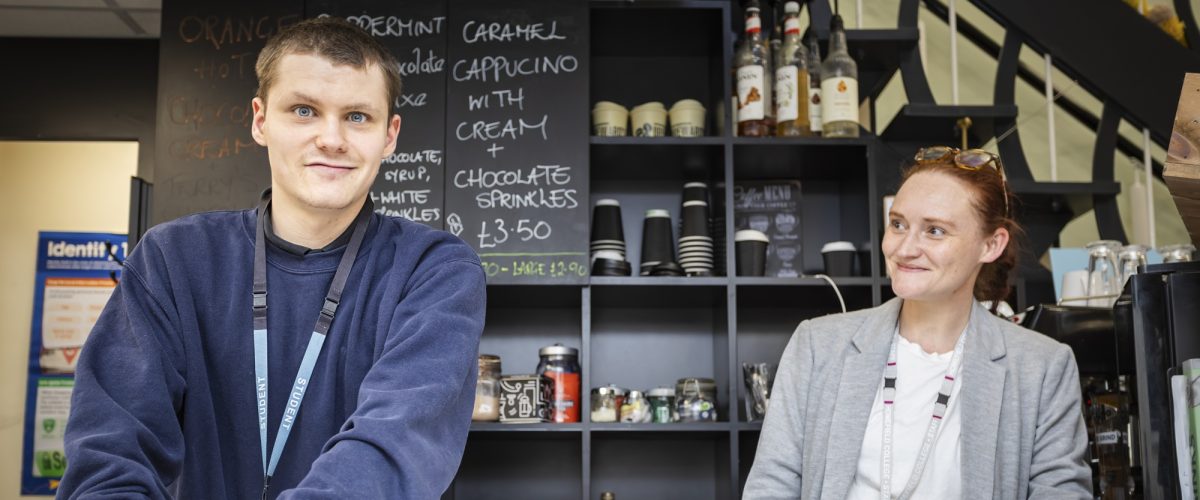 Student and staff member behind the serving bar at a coffee shop